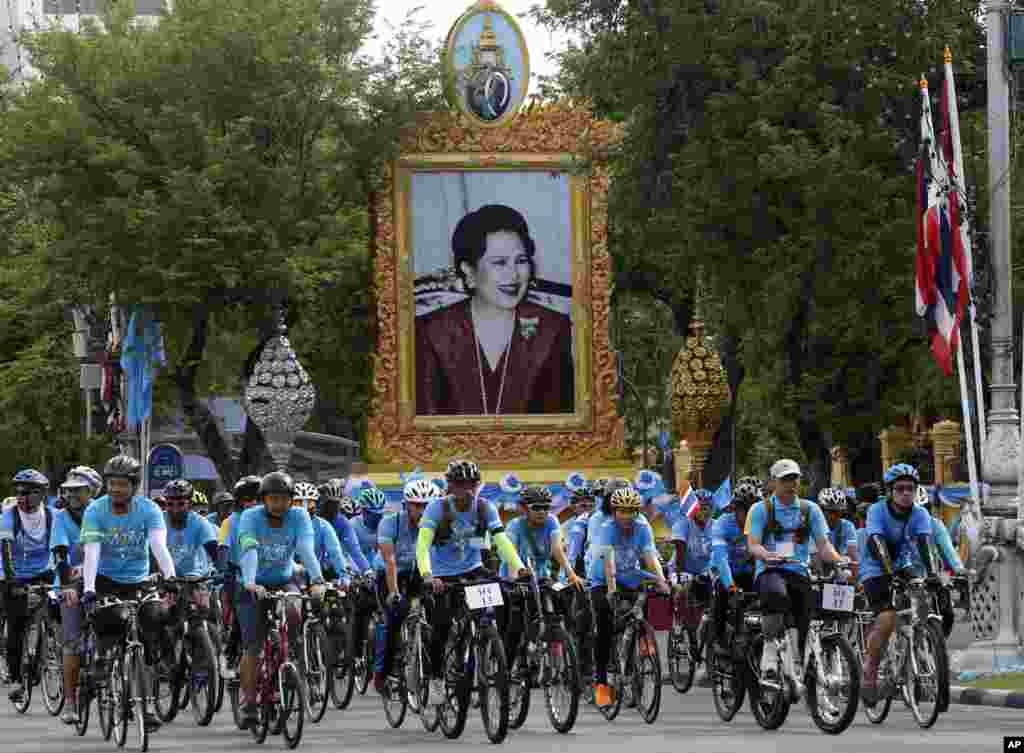 태국 방콕에서 마하 와찌랄롱꼰 태국 왕세자가 이끄는 자건거 행렬이&nbsp;시리킷 왕비의 초상화 옆을 지나고 있다. 이 날 행사는 시리킷 왕비의 83세 생일을 기념하기 위해 열렸다.
