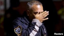 A police officer wipes tears from his face as he walks away from the site where two New York City police officers were shot dead in the Brooklyn borough of New York, Dec. 20, 2014. 