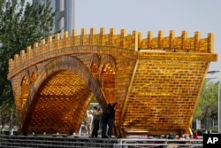 2017年4月18日，工人们在中国国家会议中心外头的平台上，为丝绸之路黄金大桥装置缆线。北京将于5月在国家会议中心举办一带一路峰会。