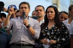 Honduran President Juan Orlando Hernandez, accompanied by his wife Ana Garcia, addresses supporters during a rally outside the Presidential House, in Tegucigalpa, Aug. 6, 2019.