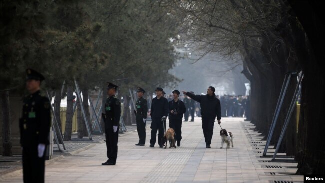 中国武警在即将召开两会的北京人大会堂附近街道上站岗，携带警犬的保安人员在巡逻。（2019年3月3日）