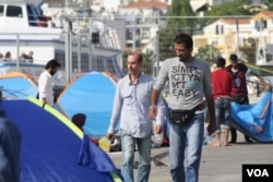 Refugees and other migrants arrive in Greek islands on dangerous boats before boarding a commercial ship to Athens. Those without enough money for the ship are left behind. (H. Murdock/VOA)