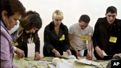 Para petugas menghitung surat suara pada referendum di kota Simferopol, Krimea, Minggu (16/3). 