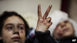 Hana, 12, flashes the victory sign next to her sister Eva, 13, as they recover from severe injuries after the Syrian Army shelled their house in Idlib, north Syria. (March 10, 2012 file photo)