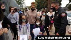 Nicole Tschabourian, 8, (L) and Leah Yousefi, 8, arrive with printed barcodes for the first day of school and return to full-time in-person learning after the coronavirus disease (COVID-19) break, in Glendale, Los Angeles, California, U.S., August 18, 202