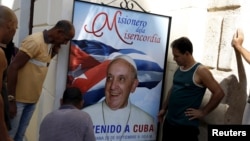 People hang up a poster with a photograph of Pope Francis in Havana, Cuba, Sept. 18, 2015. 