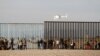 Migrants, part of a caravan of thousands trying to reach the U.S., look through the border fence between Mexico and the United States after arriving in Tijuana, Mexico, Nov. 13, 2018.