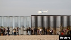 Migrants, part of a caravan of thousands trying to reach the U.S., look through the border fence between Mexico and the United States after arriving in Tijuana, Mexico, Nov. 13, 2018.