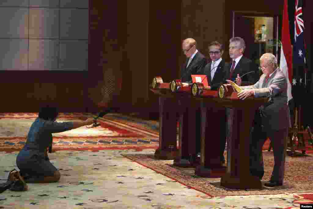 A reporter (L) holds a microphone during a joint news conference of Australia&#39;s Defense Minister Stephen Smith (2nd R) and Foreign Minister Bob Carr (4th R) with Indonesia&#39;s Foreign Minister Marty Natalegawa (3rd R) and Defense Minister Purnomo Yusgiantoro (R) at the Foreign Ministry office in Jakarta, Indonesia.