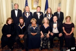 Teresa Heinz Kerry, front row, from left, Kennedy Center Honorees Al Pacino, Mavis Staples, Martha Argerich, James Taylor, and Kennedy Center President Deborah Rutter; rear row, from left, Secretary of State John Kerry, Kennedy Center Honorees Joe Walsh, Don Henley, and Timothy Schmit, and David Rubinstein are photographed following the State Department for the Kennedy Center Honors gala dinner, Dec. 3, 2016, in Washington.