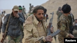 Shi'ite fighters carry weapons during a battle with Islamic State militants in Tal Afar, Iraq, Nov. 16, 2016.