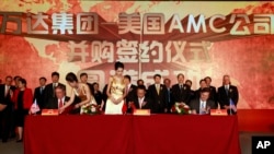 Gerry Lopez, CEO of AMC Entertainment Holdings, left, Zhang Lin, Vice President of Wanda, center, and Eliot Merrill, representative of AMC shareholders, right, sign documents during a ceremony for Dalian Wanda Group Co. to acquire AMC Entertainment.