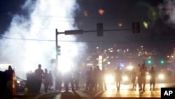 18일 미국 미주리주 퍼거슨 시에서 흑인 청년이 백인 경찰의 총에 맞아 사망한 사건에 항의하는 시위가 계속된 가운데, 시위대 주변으로 경찰이 발사한 최루탄 연기가 피어오르고 있다.