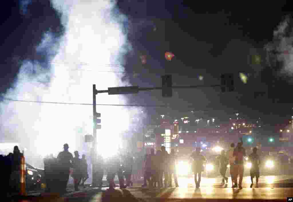 Protesters walk through a cloud of tear gas Monday, Aug. 18, 2014, in Ferguson, Missouri. (AP Photo/Jeff Roberson)