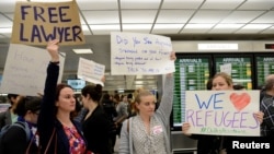 Lawyers offer free counseling as they join dozens of pro-immigration demonstrators cheering and holding signs as international passengers arrive at Dulles International Airport to protest President Donald Trump's travel ban in suburban Washington, Jan. 29