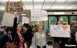 Lawyers offer free counseling as they join dozens of pro-immigration demonstrators cheering and holding signs as international passengers arrive at Dulles International Airport to protest President Donald Trump's travel ban in suburban Washington, Jan. 29