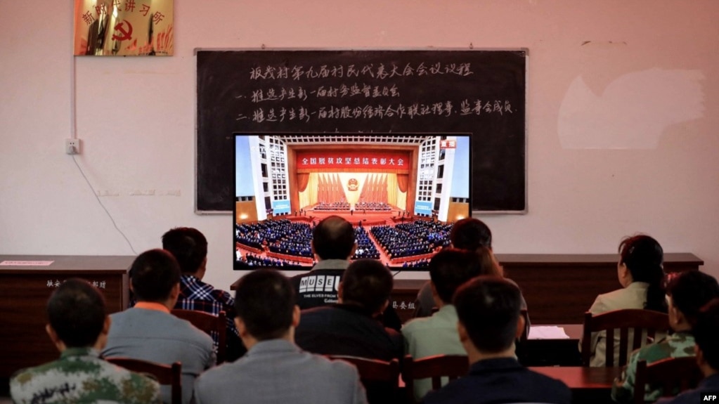广西柳州一个村庄的村民正在观看在北京人大会堂举行的全国脱贫攻坚总结表彰大会的电视直播。（2021年2月25日）