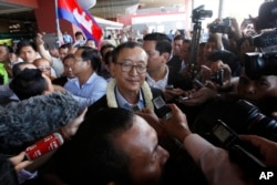 FILE - Sam Rainsy, center, leader of the opposition Cambodia National Rescue Party (CNRP), talks to journalists upon his arrival at Phnom Penh International Airport in Phnom Penh, Cambodia, Aug. 16, 2015.