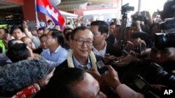 FILE - Sam Rainsy, center, leader of the opposition Cambodia National Rescue Party (CNRP), talks to journalists upon his arrival at Phnom Penh International Airport in Phnom Penh, Cambodia, Aug. 16, 2015.