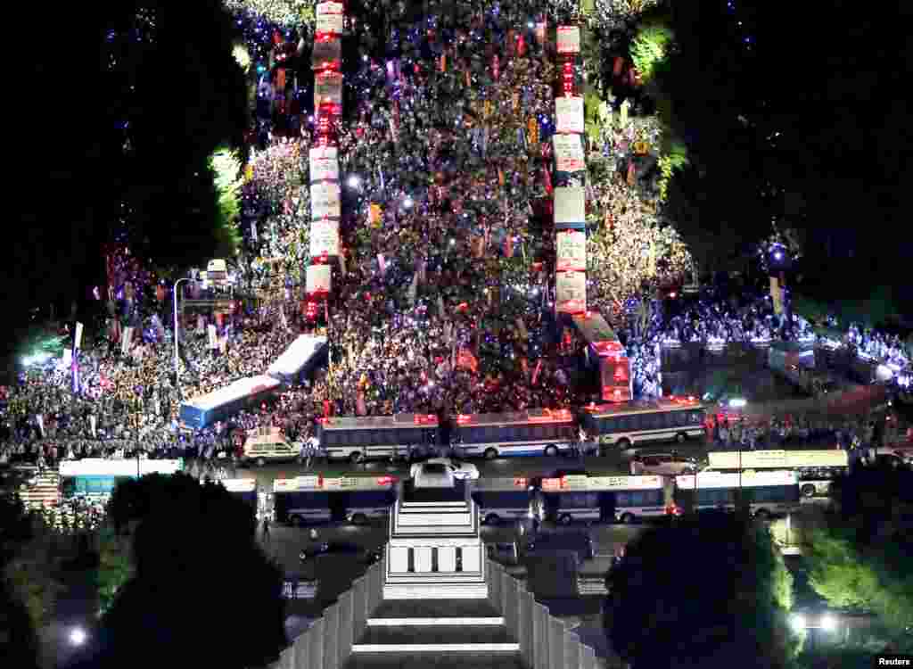 Thousdands of protesters rally against Japan's Prime Minister Shinzo Abe's security bill and his administration, as police use parked buses to block protesters in front of the parliament building (bottom) in Tokyo, in this photo taken by Kyodo.
