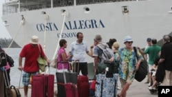 Passengers of the Costa Allegra cruise ship wait to board on a ferry at Victoria's harbor, Seychelles, March 1, 2012.