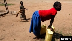 A girl prepares to lift a jerry can of water onto her head in the village of Loro in the Oyam district of northern Uganda.