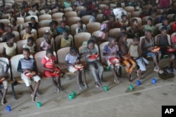 Children sit on benches in a hall after receiving food and drinking water at a temporary shelter for children in Pemba city, on the northeastern coast of Mozambique, May 2, 2019.