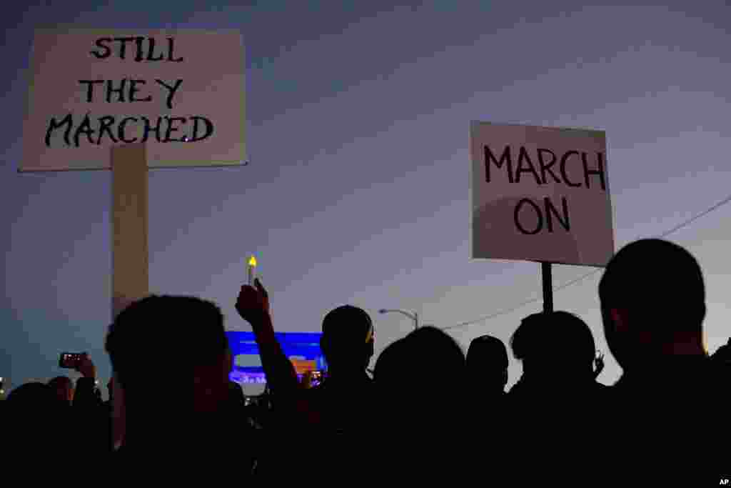 Marchers hold up signs as they make their way towards the Edmund Pettus Bridge in honor of Martin Luther King, Jr., in Selma, Alabama, Jan. 18, 2015.