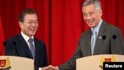 韩国总统文在寅在新加坡总统府与新加坡总理李显龙握手。（2018年7月12日）