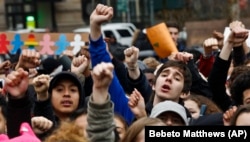 In New York's Foley Square, students from high schools and colleges protest with clenched fists, during a rally against President Donald Trump's executive order banning travel from seven Muslim-majority nations.