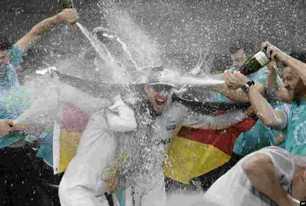 Mercedes driver Nico Rosberg of Germany celebrates with his wife Vivian Sibold holding a German flag in the team garage after winning the F1 2016 Championship in the Emirates Formula One Grand Prix at the Yas Marina racetrack in Abu Dhabi, United Arab Emirates.