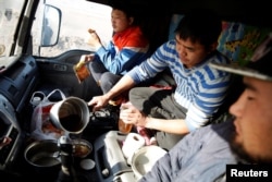 Three men eat a dinner of instant noodles and dried beef inside a truck. Bataa Davaasuren, director of Mongolia's Customs House at Gashuun Sukhait, said customs on both sides of the border were short-staffed.