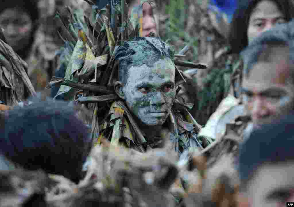 Devotees covered in mud and wearing costumes made from banana leaves attend mass as they take part in a religious festival in honor of St. John the Baptist, also known locally as the "mud people" festival in Aliaga, Nueva Ecija province, north of Manila, Philippines.