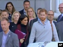 In this image made from video, Britain's Prince Harry, center right, and his wife Meghan, center left, Duke and Duchess of Sussex, approach a car at an airport in Sydney, Oct. 15, 2018.