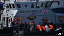 Pejabat Pasukan Perbatasan Inggris memindahkan migran yang dicegat saat bepergian dengan RIB dari Perancis ke Dover, Inggris tenggara pada 13 Agustus 2021. (Foto: AFP)