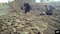 A local resident clears debris of his collapsed mud house following an earthquake in the town of Dalbandin on 19 Jan. 2011.