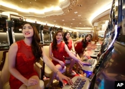 FILE - Casino models pose at the slot machines during the media tour of Solaire Casino in the Philippines. Casino chips are commonly used to launder money because the exchanges quickly become anonymous.