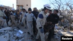 Warga dan relawan mengangkut korban dari reruntuhan rumah sakit yang dikelola oleh organisasi bantuan Medecins Sans Frontieres (MSF) atau Dokter Tanpa Tapal Batas - yang hancur terkena misil di Marat Numan, Idlib, Suriah (16/2). PBB mengumumkan konvoi bantuan sedang dikirim ke kota-kota yang terkepung.