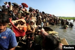 Rohingya refugees who fled from Myanmar wait to be let through by Bangladeshi border guards after crossing the border in Palang Khali, Bangladesh, Oct. 16, 2017.