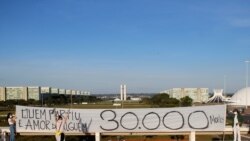 Artists hold a banner reading "Who's gone is someone's love, 30,000 dead" amid the coronavirus disease (COVID-19) outbreak in Brasilia