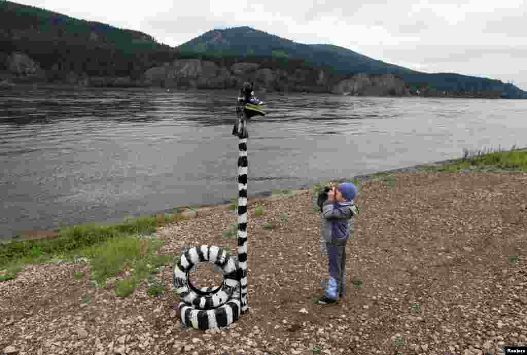 A boy takes a picture with a Soviet-made film camera of an art installation on a bank of the Yenisei River in the village of Ovsyanka, some 24km (15 miles) south of Russia&#39;s Siberian city of Krasnoyarsk.&nbsp;