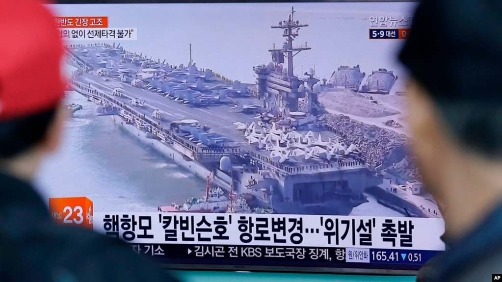 La gente ubicada en la estación de trenes de Seúl en Corea del Sur, ve un programa de noticias de televisión que muestra una imagen de archivo del portaaviones USS Carl Vinson.
