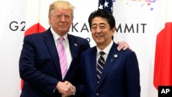 도널드 트럼프 미국 대통령과 아베 신조 일본 총리가 28일 일본 오사카에서 열린 주요20개국(G20) 정상희의에서 만나 악수하고 있다. 