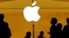 FILE - Customers walk past an Apple logo inside of an Apple store at Grand Central Station in New York, Aug. 1, 2018.