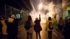 Manifestantes frente a la Universidad Amir Kabir en Teherán levantan flores mientras la policía dispara gas lacrimógeno el sábao 11 de enero. Foto: AP.