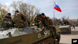 Combat vehicles with a Russian flag on one of them and gunmen on top are parked in downtown of Slovyansk, Ukraine, April 16, 2014.