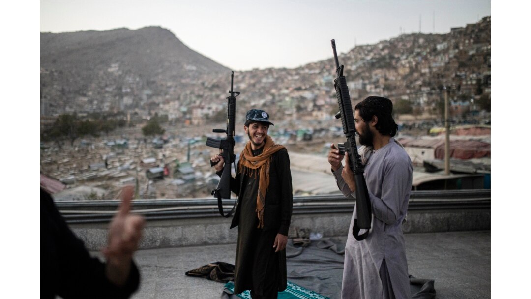 Pejuang Taliban memegang senjata mereka saat mereka berdiri di atas sebuah bangunan di kuil Kart-e-Sakhi di Kabul, Afghanistan, Selasa, 19 Oktober 2021. (AP Photo/Ahmad Halabisaz)