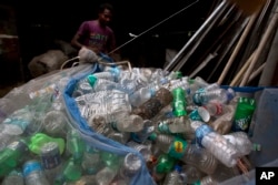 An Indian ragpicker man ties a net full of plastic bottles on the outskirts of Gauhati, India, June 5, 2017.