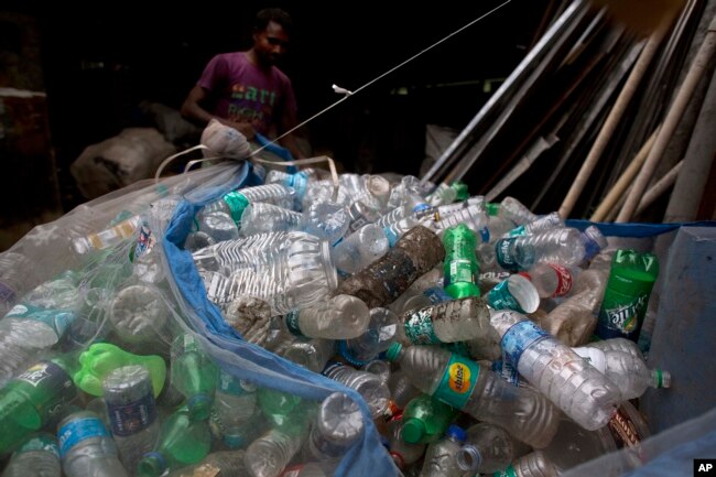 An Indian ragpicker man ties a net full of plastic bottles on the outskirts of Gauhati, India, June 5, 2017.