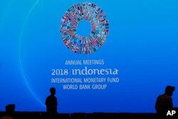 Workers pass by a banner of International Monetary Fund-World Bank annual meetings at a conference room in Bali, Indonesia, Oct. 8, 2018.
